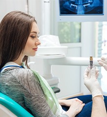 dentist showing dental implant to patient