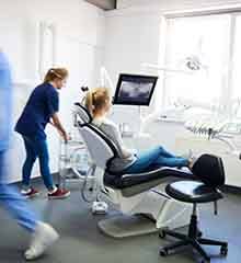 A blurred view of dentists and a woman in a dentist's clinic