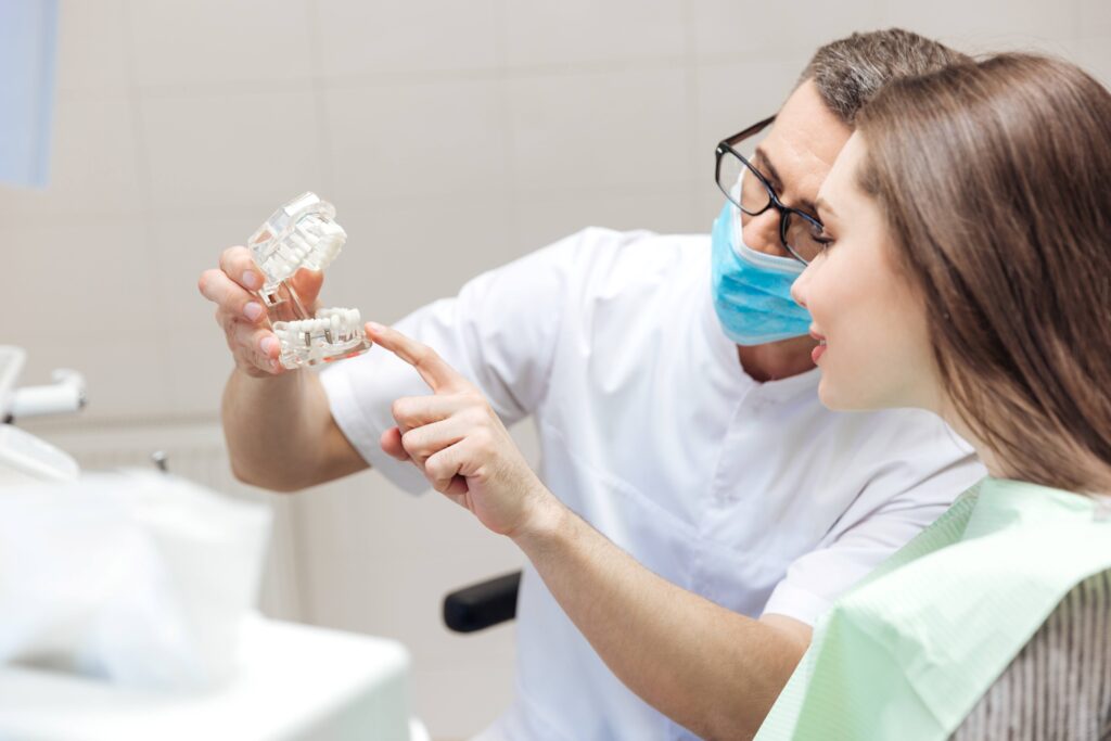 Dentist showing patient model of dental implant